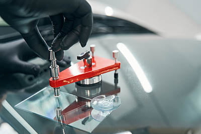 Closeup repair of cracked car windshield. Auto windshield crack fixing Closeup repair of cracked car windshield. Auto windshield crack fixing. Professionally repairing